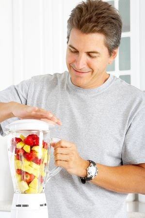 Happy man juicing with regular blender